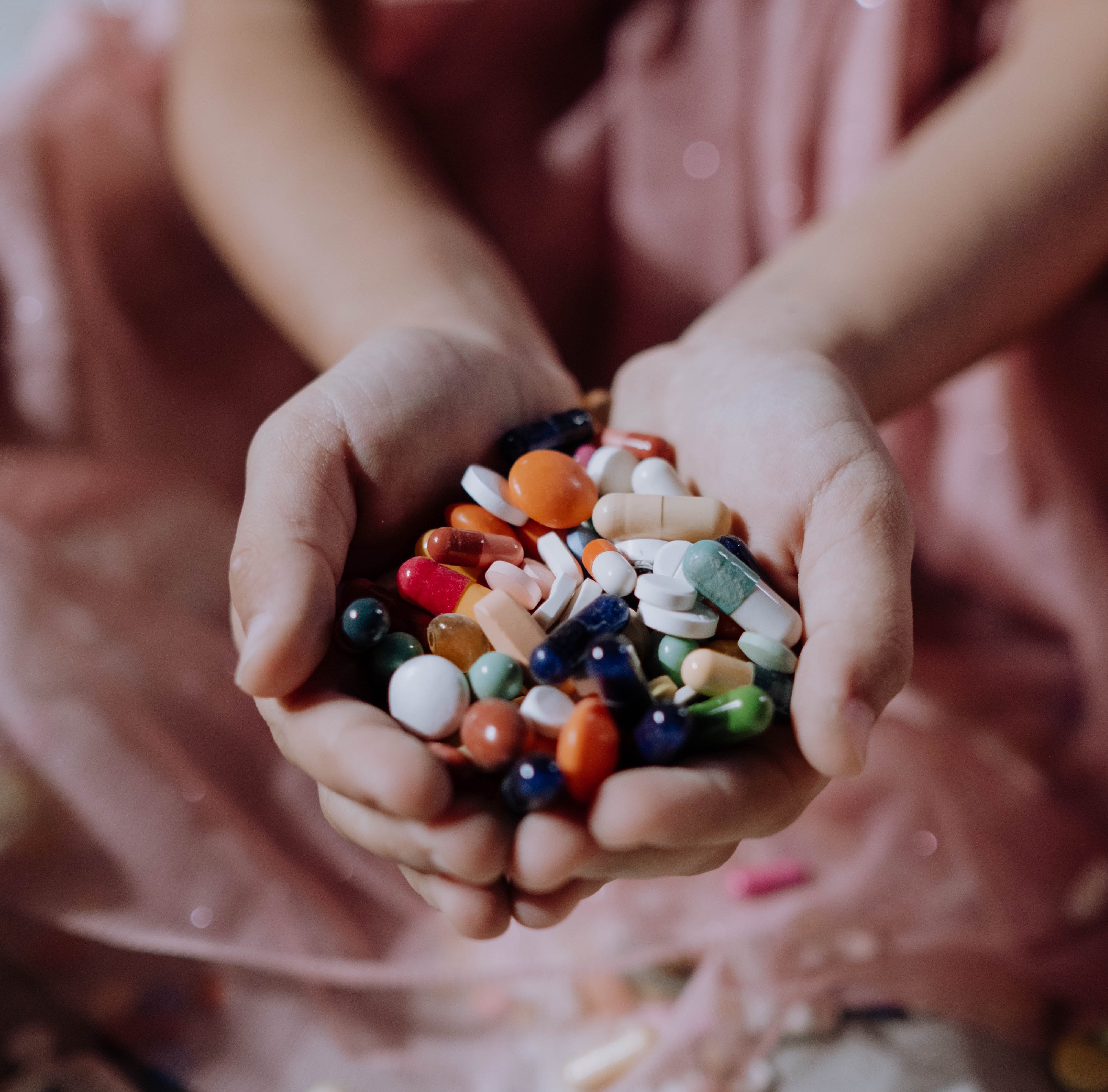 Hands holding a variety of medical pills