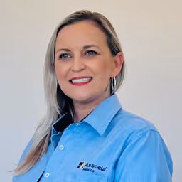 Smiling woman with long blonde hair wearing a blue Associa shirt and hoop earrings.