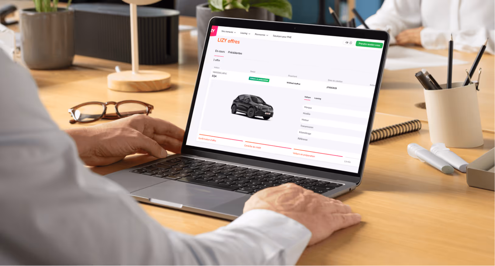 Person using a laptop displaying a car leasing management interface with a black compact car image.