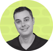 A man with short dark hair smiles softly against a bright green, patterned background.