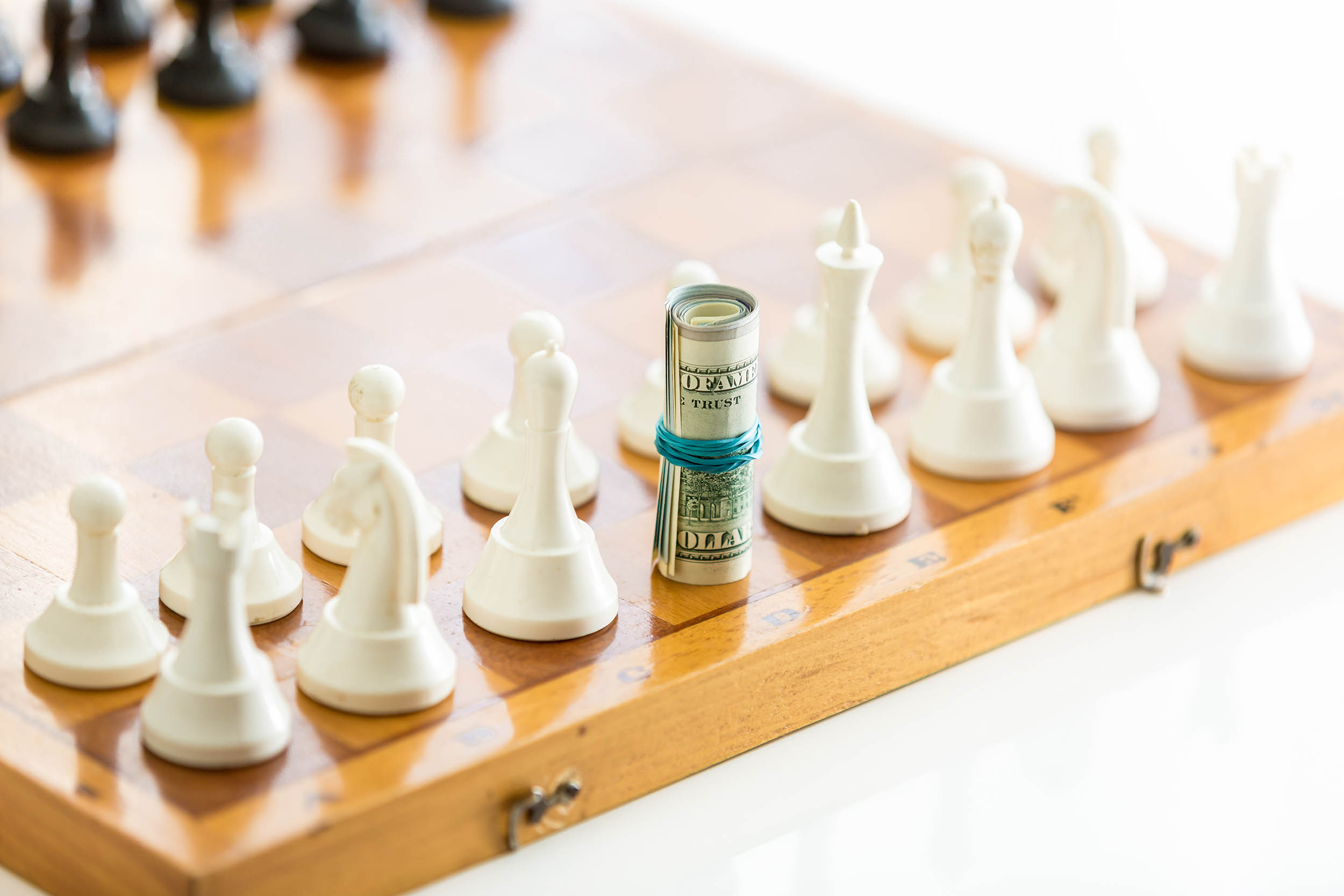 Cash and chess pieces, representing strategic decisions behind sustainable advisory programs