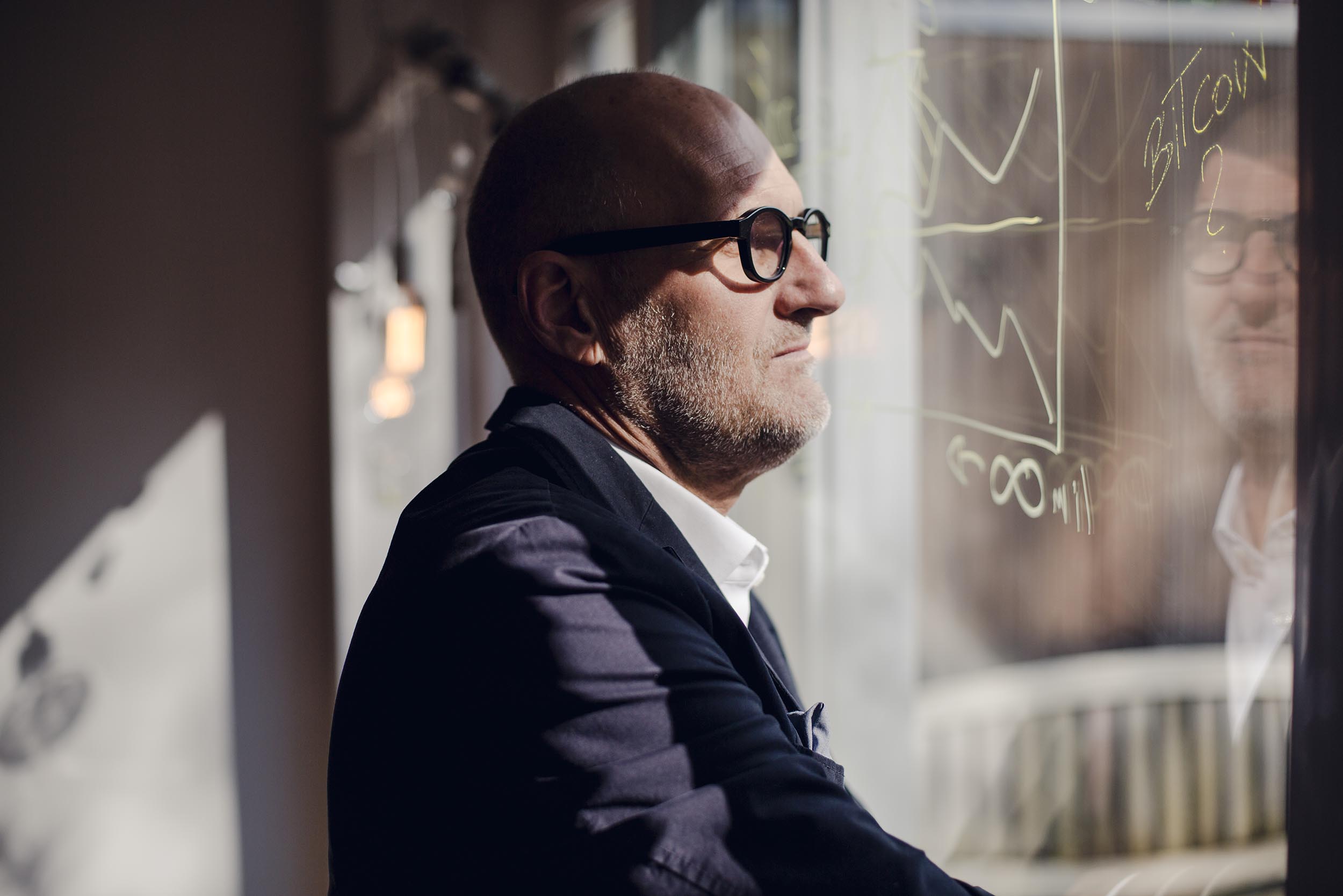 Man looking out a window at economic graphs, representing a bumpy small-business economy