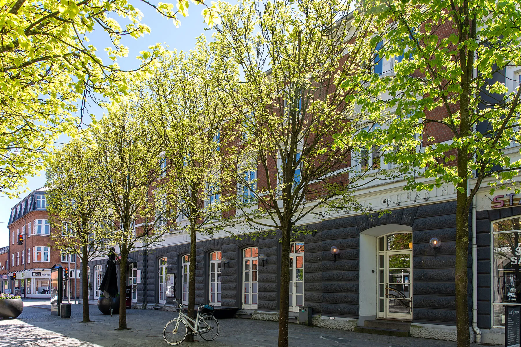 Forsiden af ejendommen i Østergade, Herning med lysegrønne træer foran