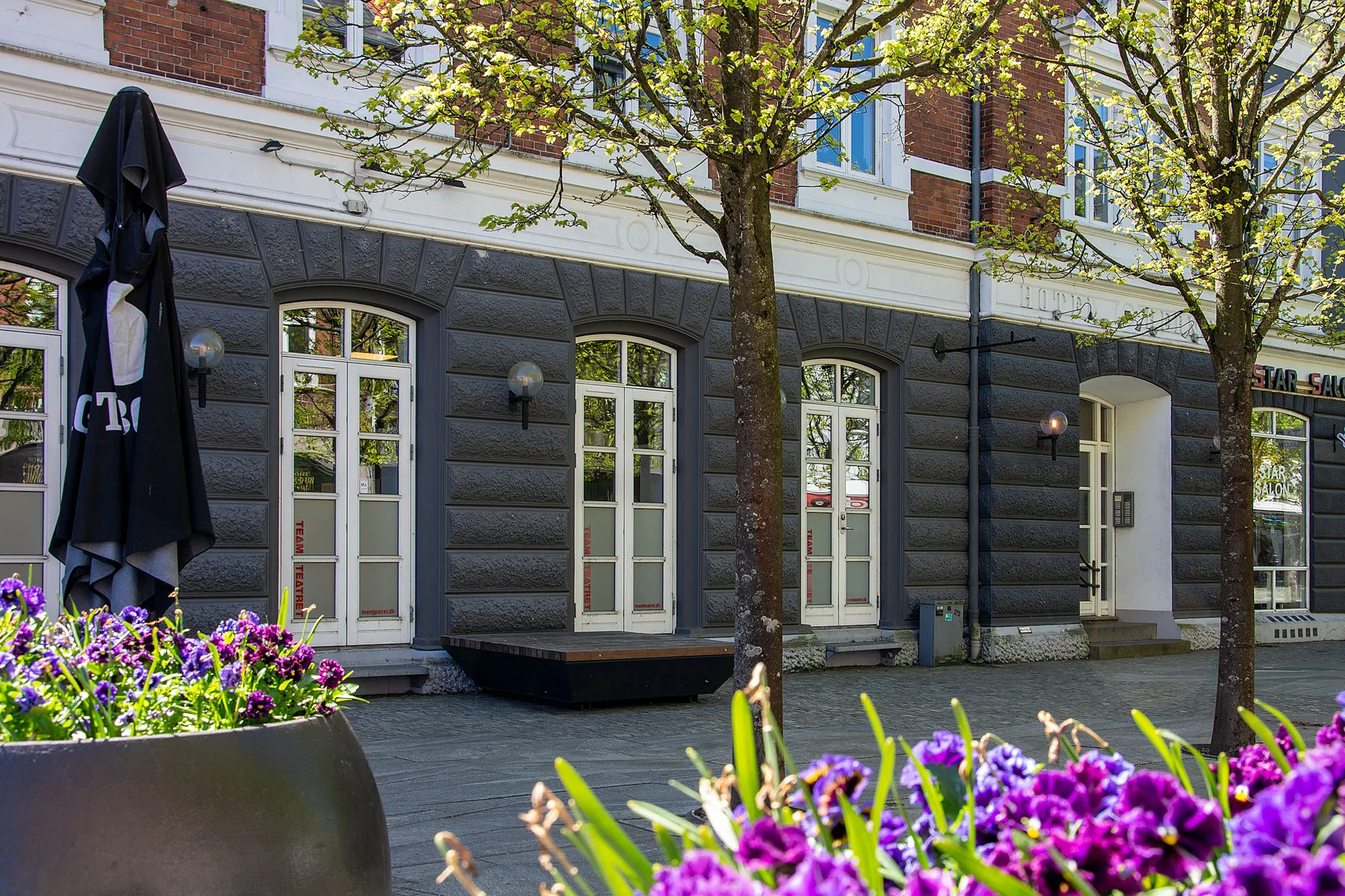 Forsiden af ejendommen i Østergade i Herning med flotte blomster i forgrunden