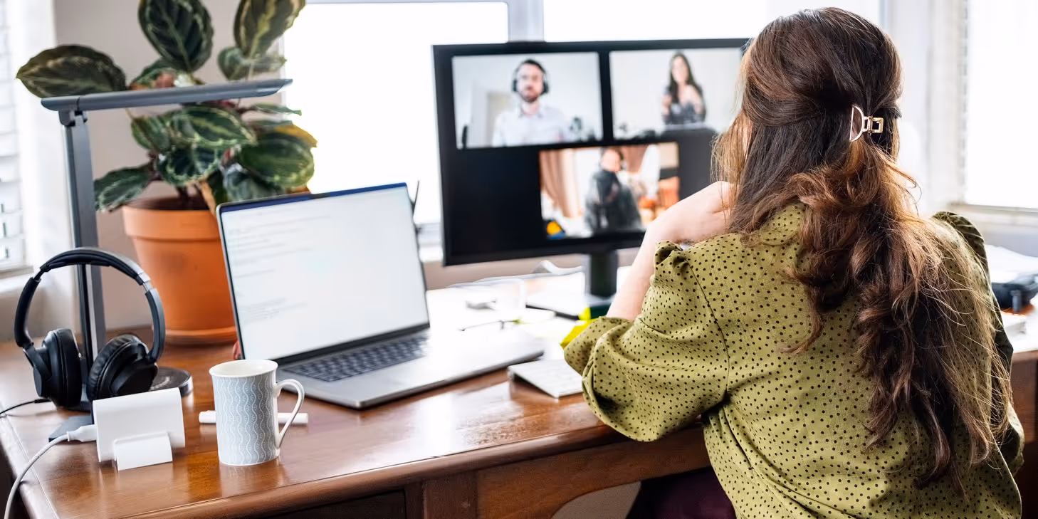 Woman attending a virtual webinar on leveraging technology with multiple participants visible on a screen.