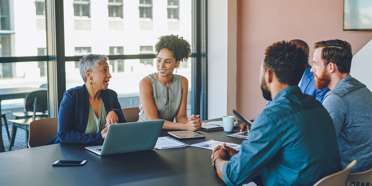 HOA board members meeting around a conference table with laptops and documents, representing board education and operational best practices training.