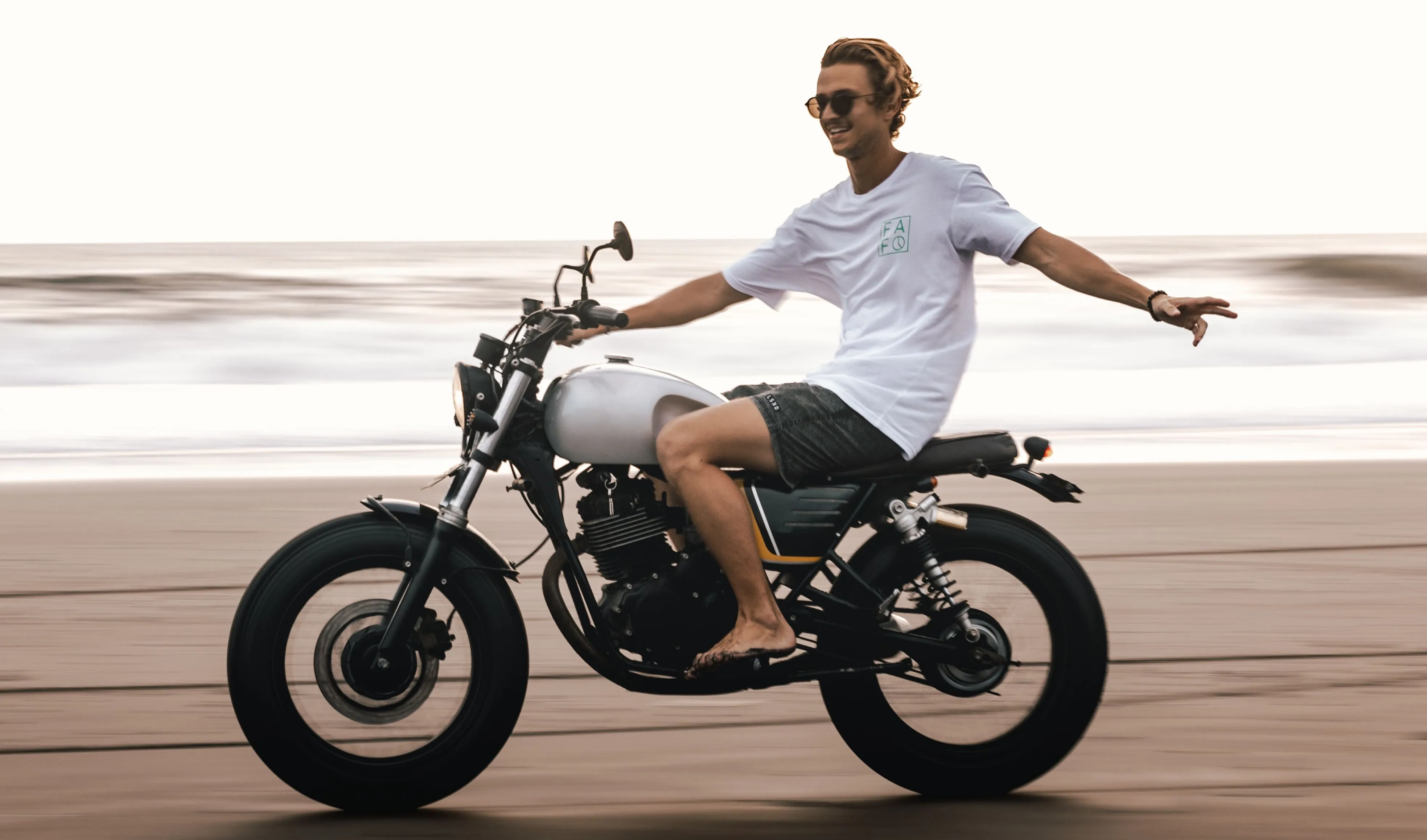 chico en moto conduciendo en la playa sin casco