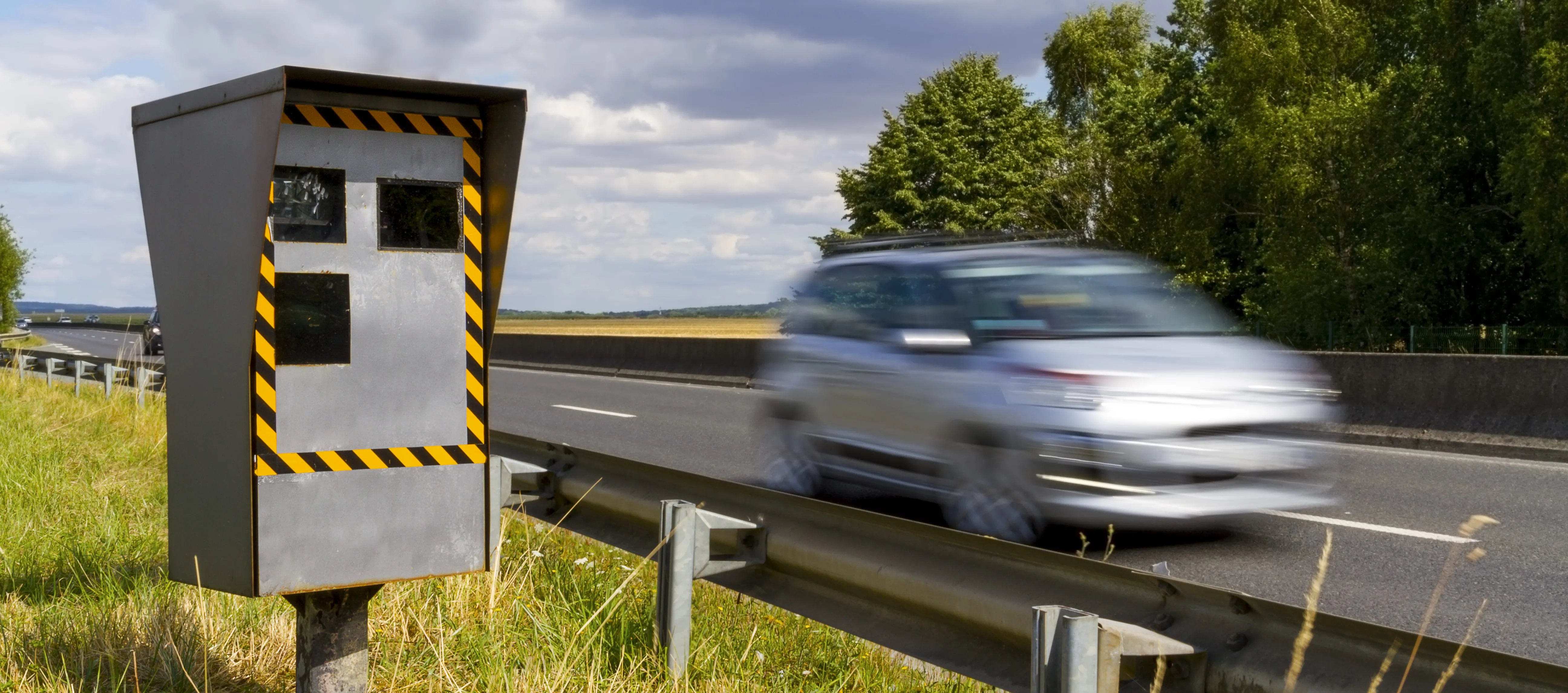  coche pasando por carretera al lado de un radar de tráfico