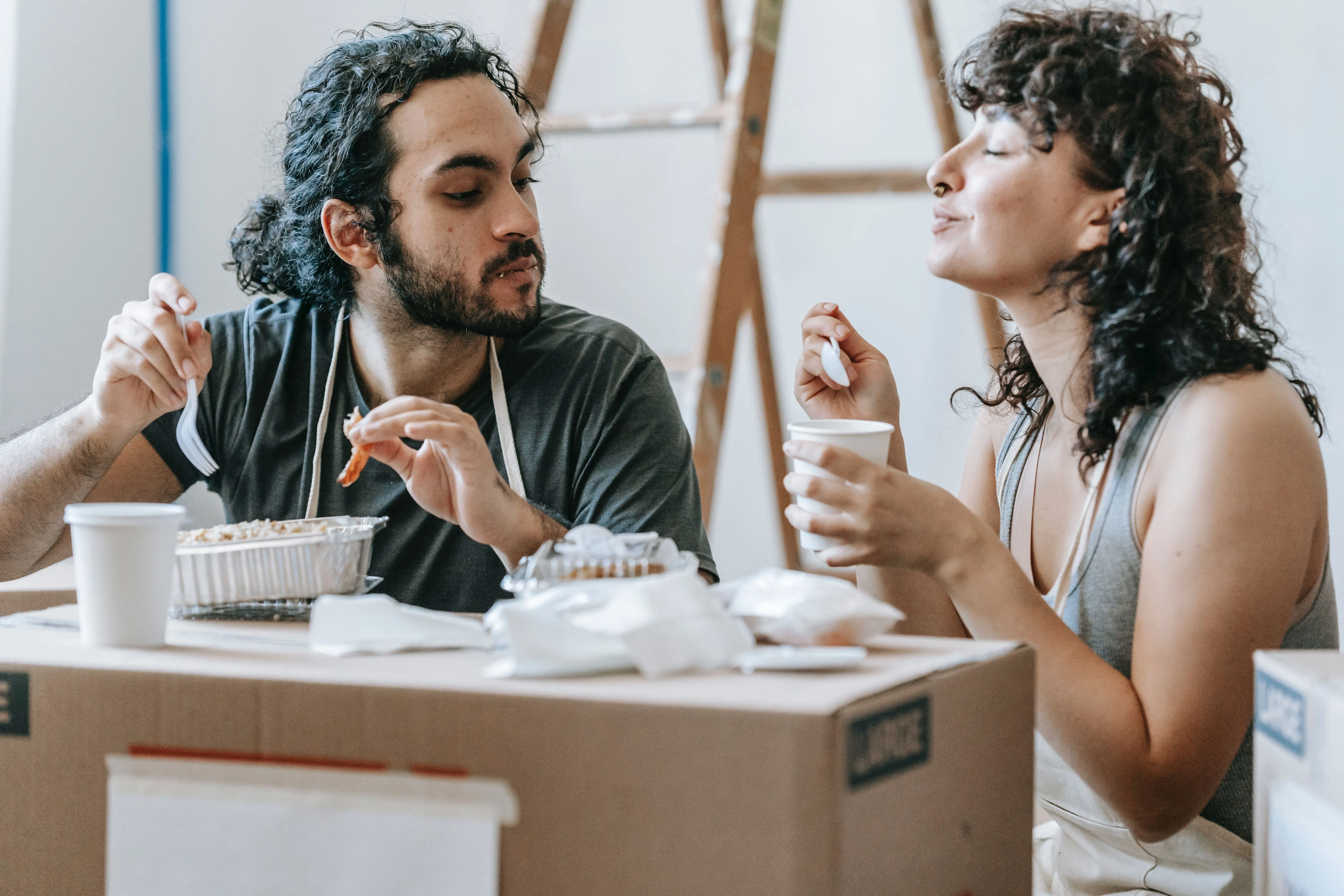 pareja sentada comiendo encima de unas cajas de cartón