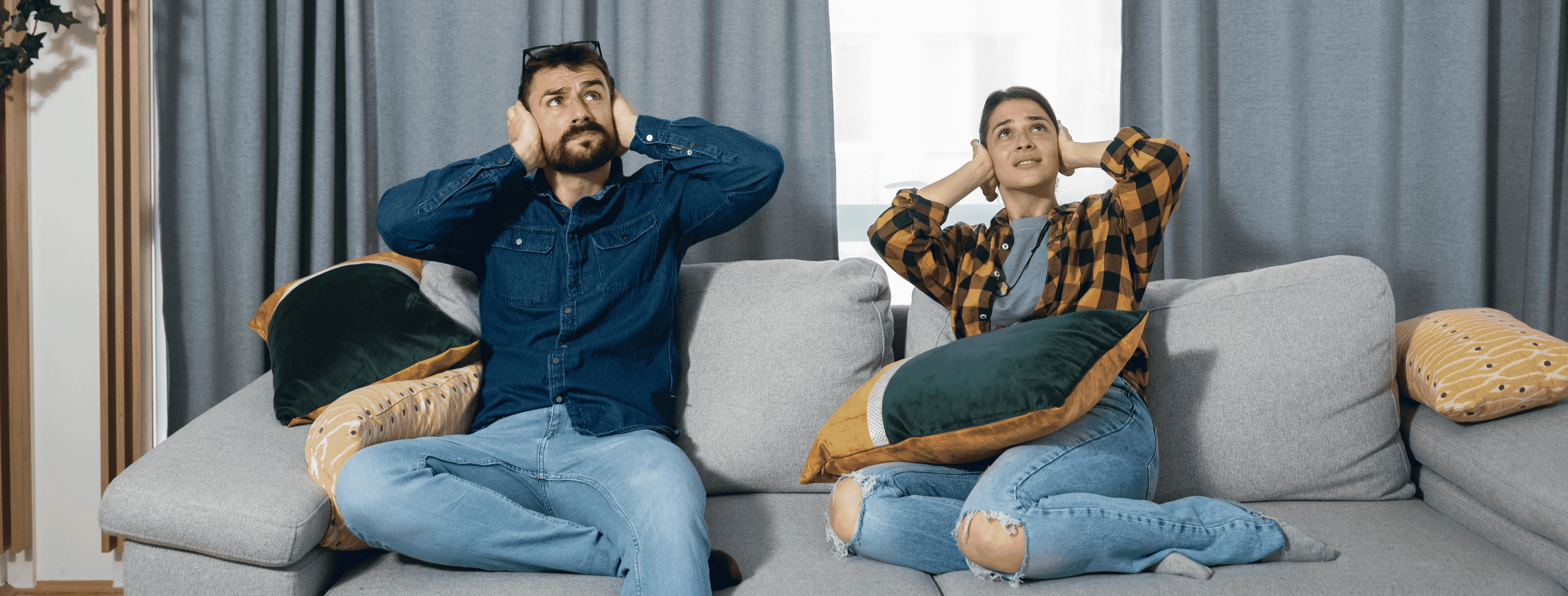 dos personas en el salón de su casa tapándose las orejas