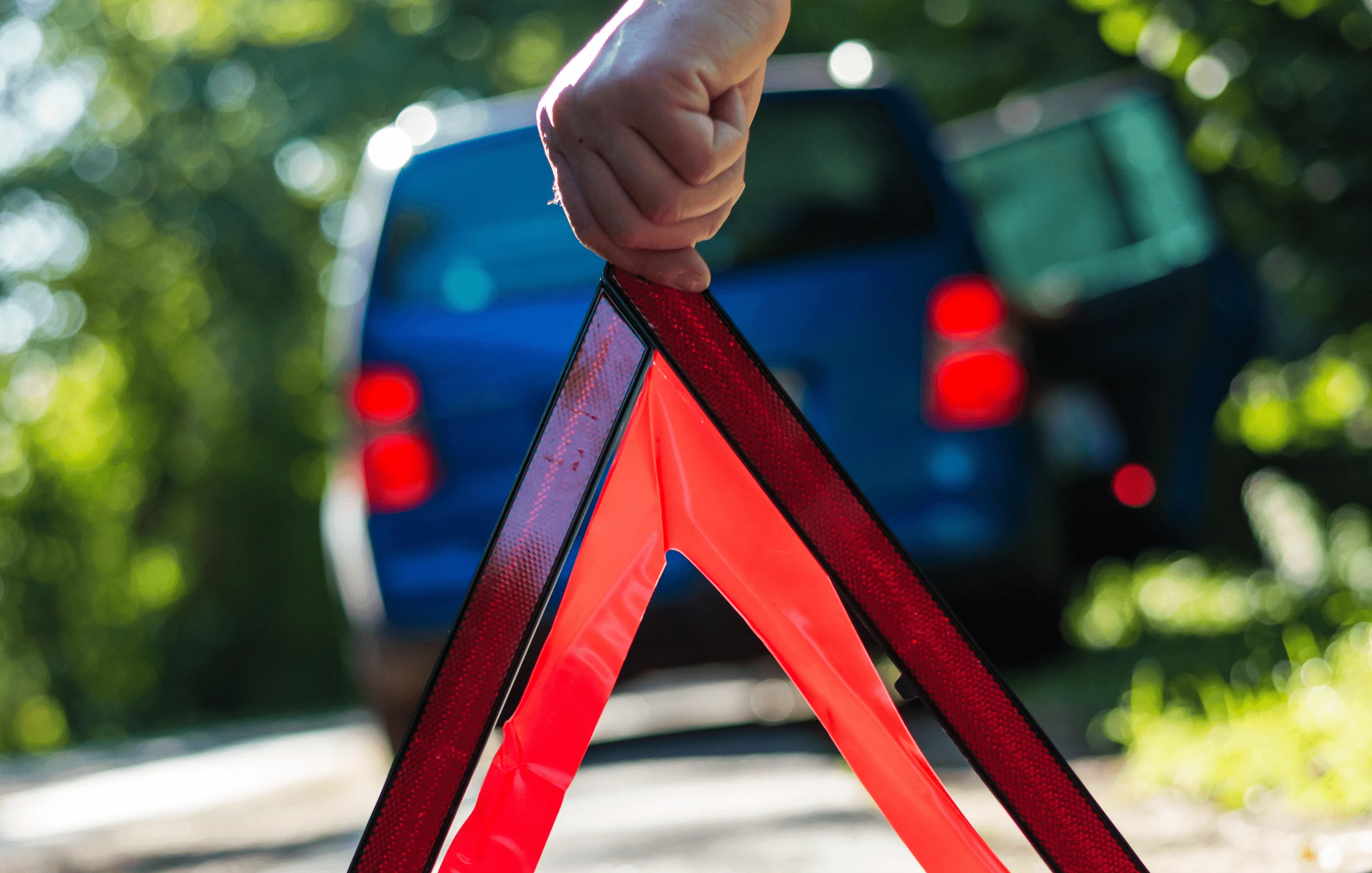 coche azul parado con mano poniendo triangulo