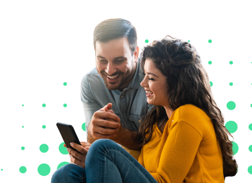 Pareja sonriente sentada, mirando un teléfono móvil, con fondo de círculos verdes.