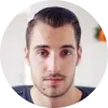 Hombre joven con cabello corto y bien peinado, mirando a la cámara en un entorno luminoso y moderno.