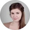 Mujer con cabello castaño claro y lacio, sonriendo, en un fondo neutro.