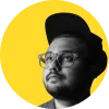Hombre con gafas y gorra, mirando hacia arriba, sobre fondo amarillo.