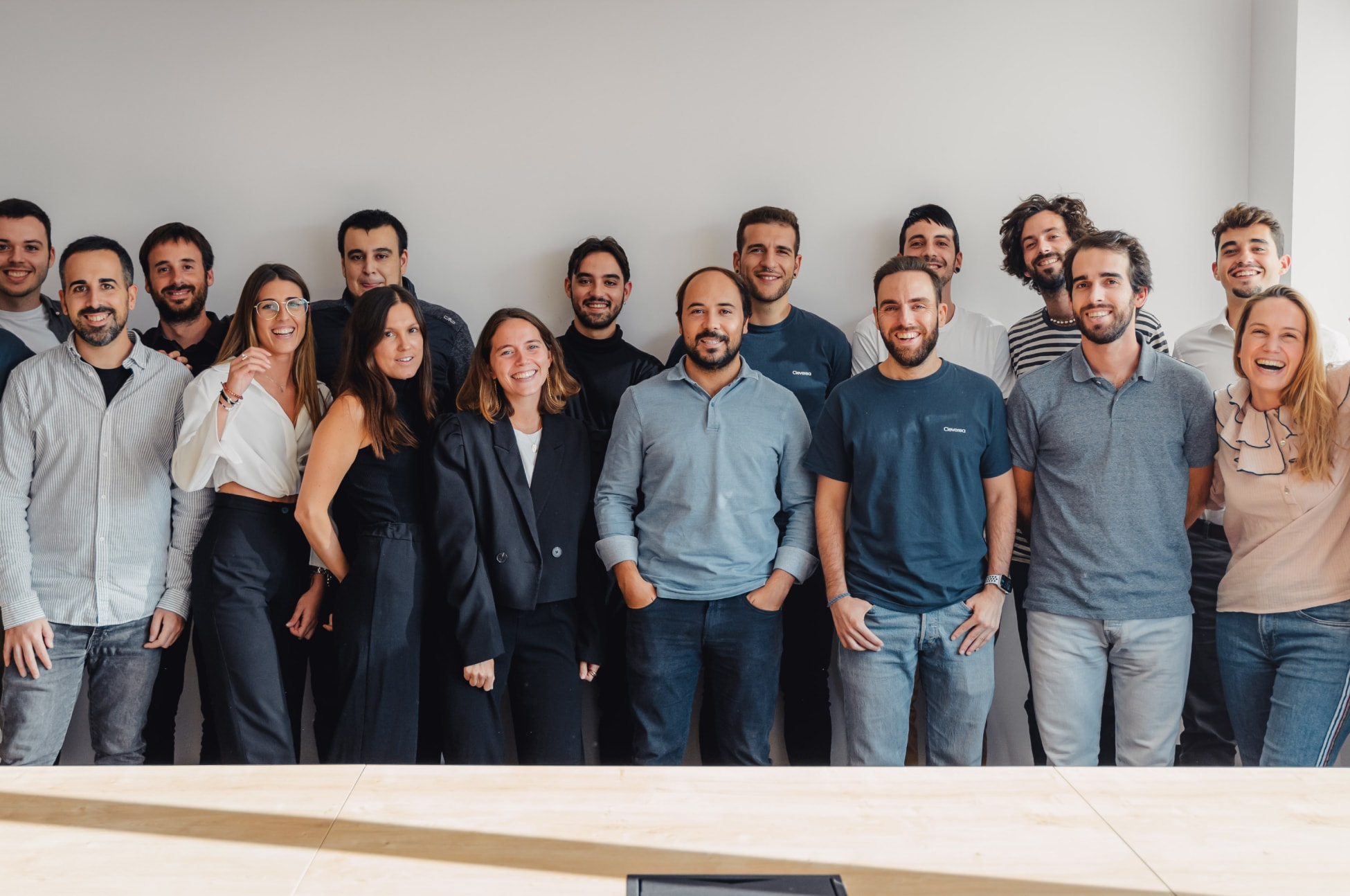 El equipo de Cleverea en 2022 sonriendo y posando en un entorno luminoso, con una mesa de madera en primer plano.