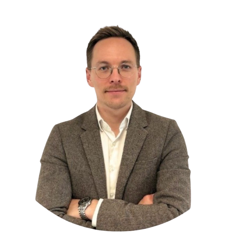Man with glasses wearing a brown blazer and white shirt, arms crossed, facing forward.