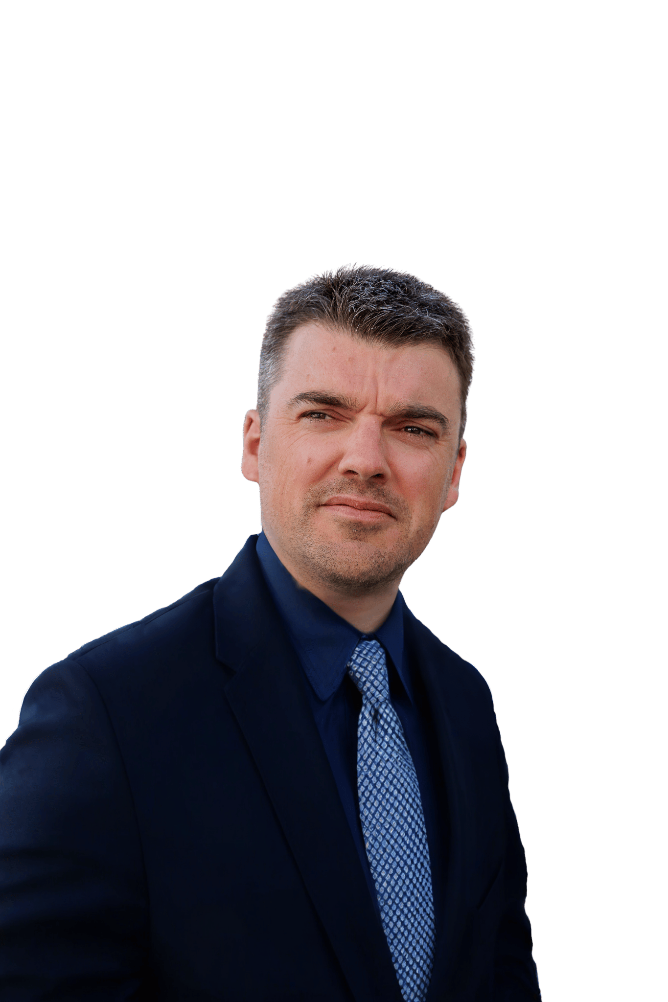 Man with short dark hair wearing a dark suit, blue shirt, and patterned blue tie, looking slightly to the right with a thoughtful expression.