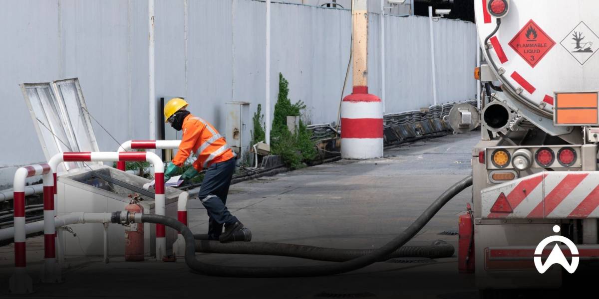 พนักงานชายกำลังต่อท่อจากถังน้ำมันของรถบรรทุก