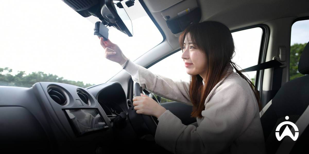 ผู้หญิงกำลังปรับกล้องหน้าที่ติดหน้ารถยนต์