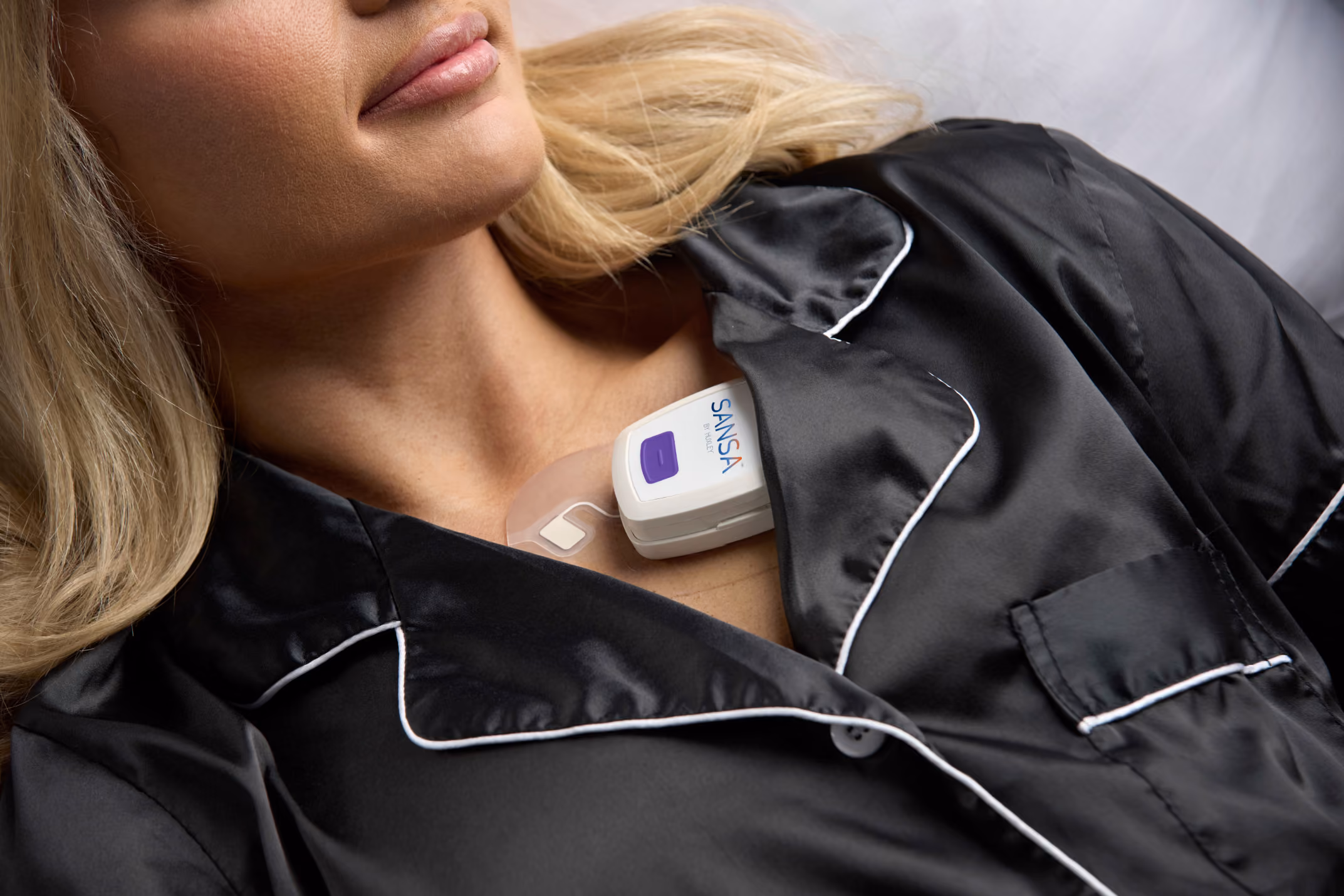 Woman in dark pajamas wearing the SANSA patch on her chest