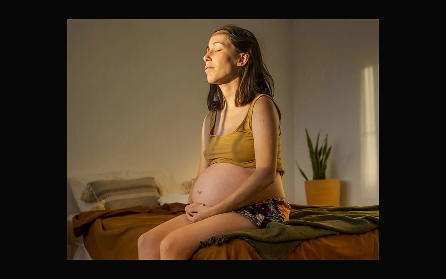 Pregnant woman sitting on a bed