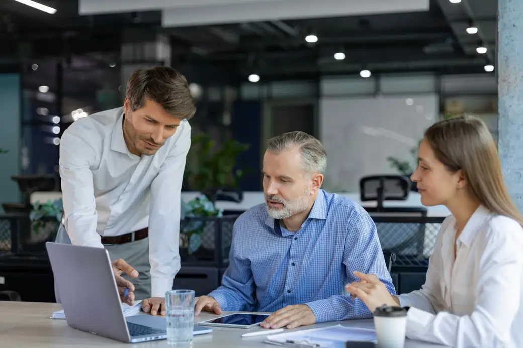 A procurement team reviewing procurement software options together on a laptop