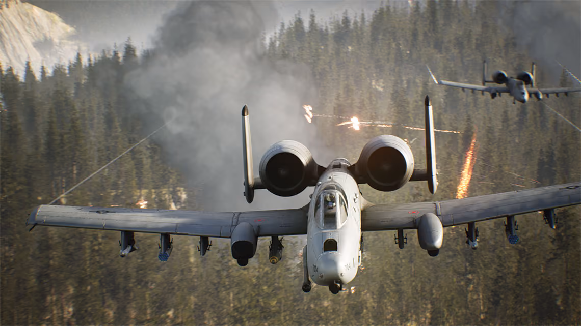 Two fighter jets fly over heavily wooded forest with rising smoke and gunfire.
