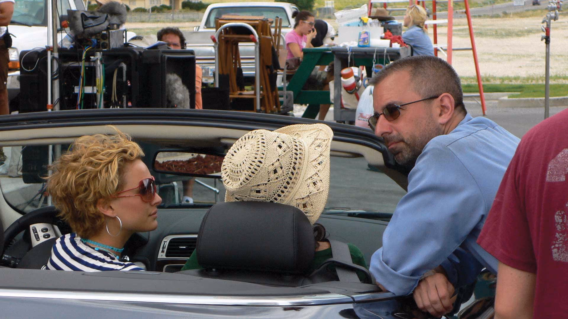 Natalie Portman and Nora Jones in an open roofed car, Trotiner leans on the passenger side door.