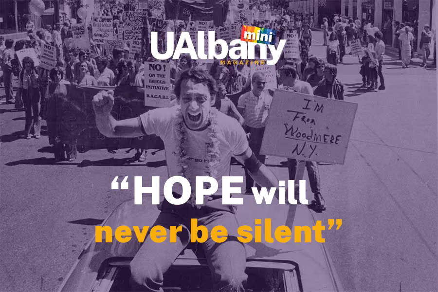 Harvey Milk sitting on a car leading a parade while holding a sign that says I am from Woodmere N.Y.