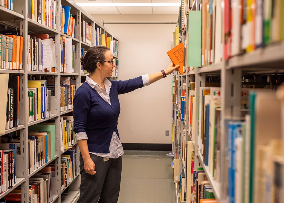 Lent removes a book from a library shelf.