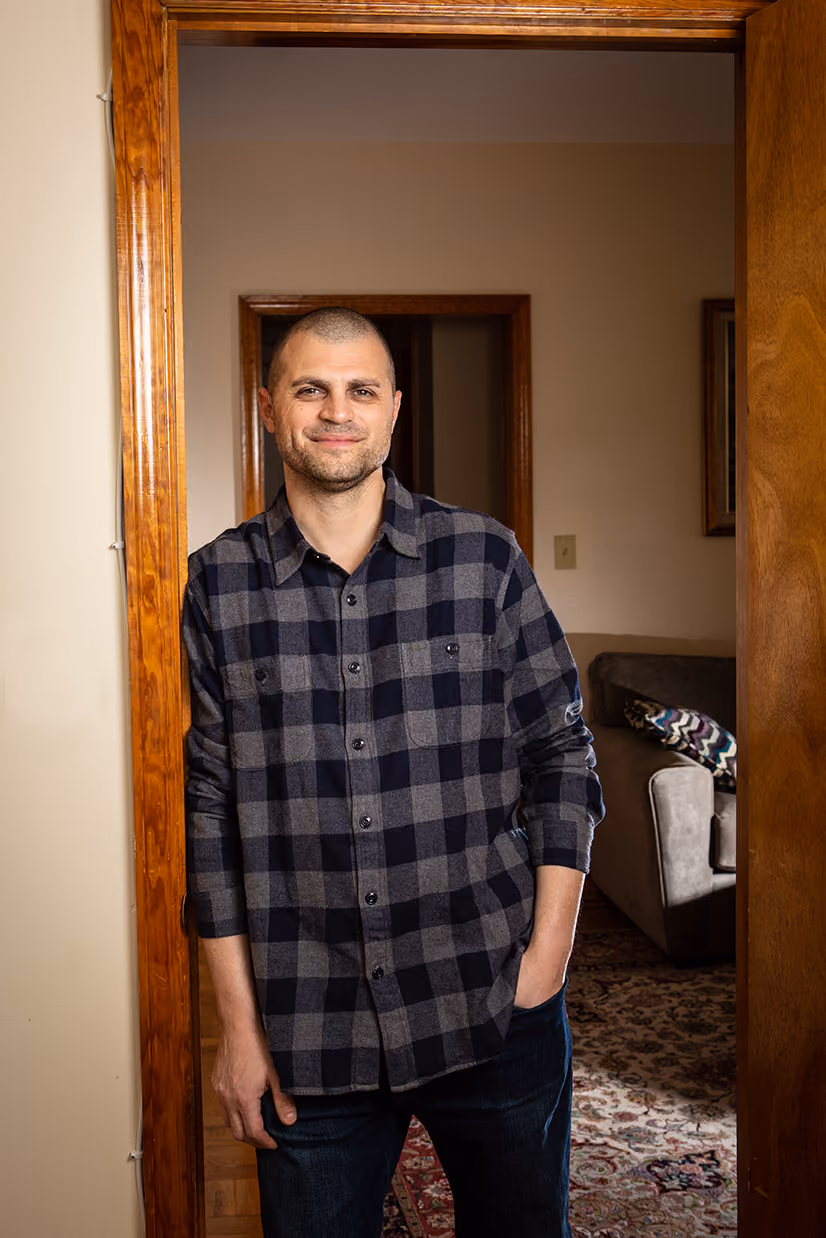 Adam Schleichkorn leaning against a doorway in his apartment.