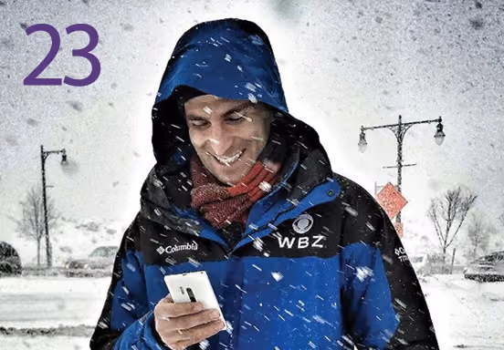 Eric Fisher looks at small mobile device while outside in a blizzard.