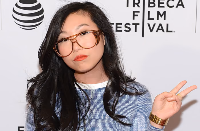 Nora Lum holds up peace sign while standing in front of a Tribeca Film Festival backdrop.