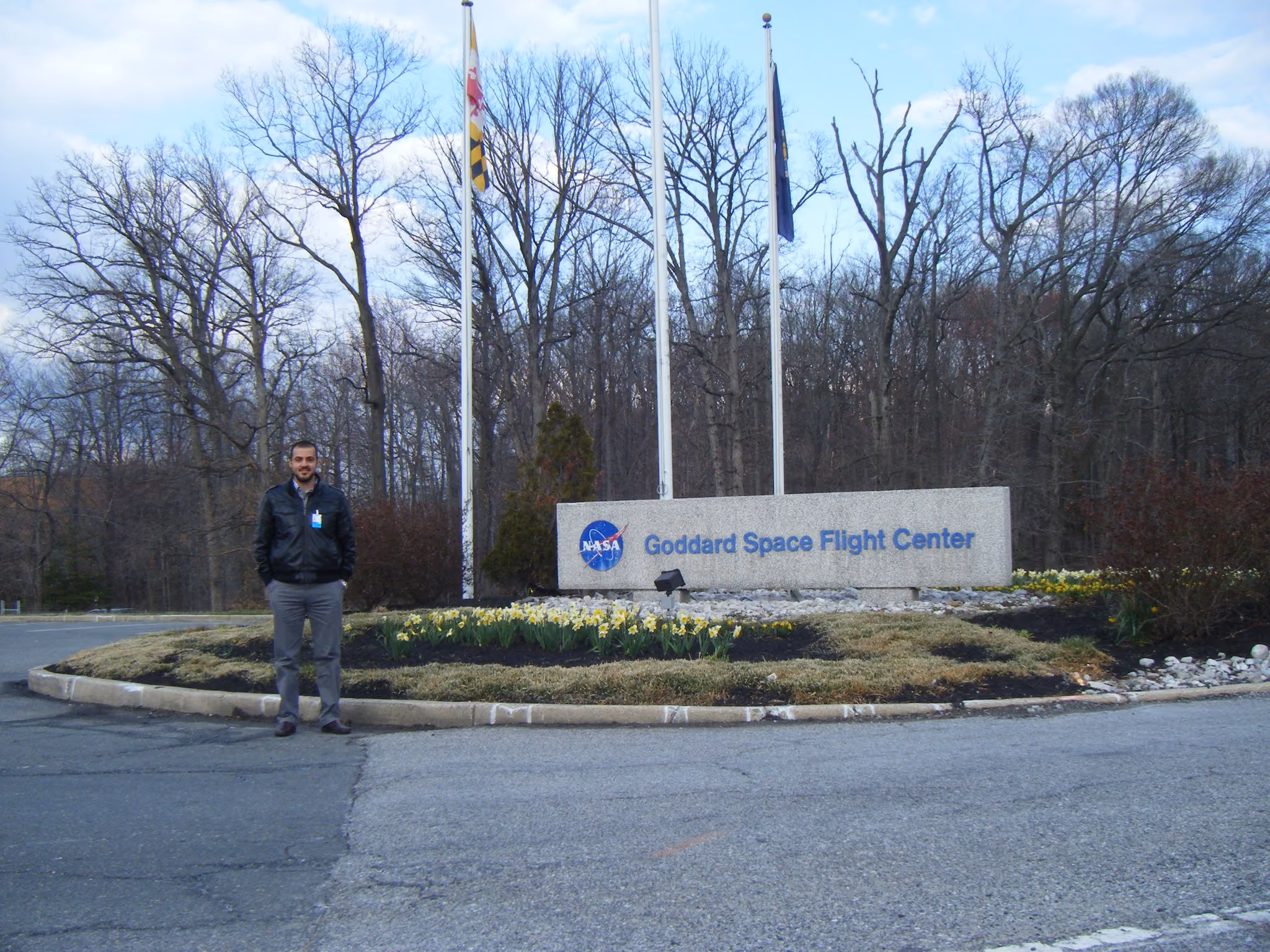 Mustafa Aksoy stands in front of exterior signage which has the NASA logo and reads "Goddard Space Flight Center"
