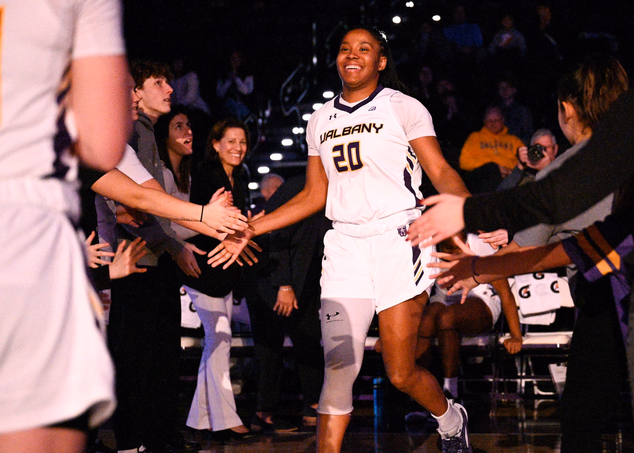 Basketball player Kayla Cooper Cooper is all smiles as she runs onto the basketball court during starting line-up introductions.