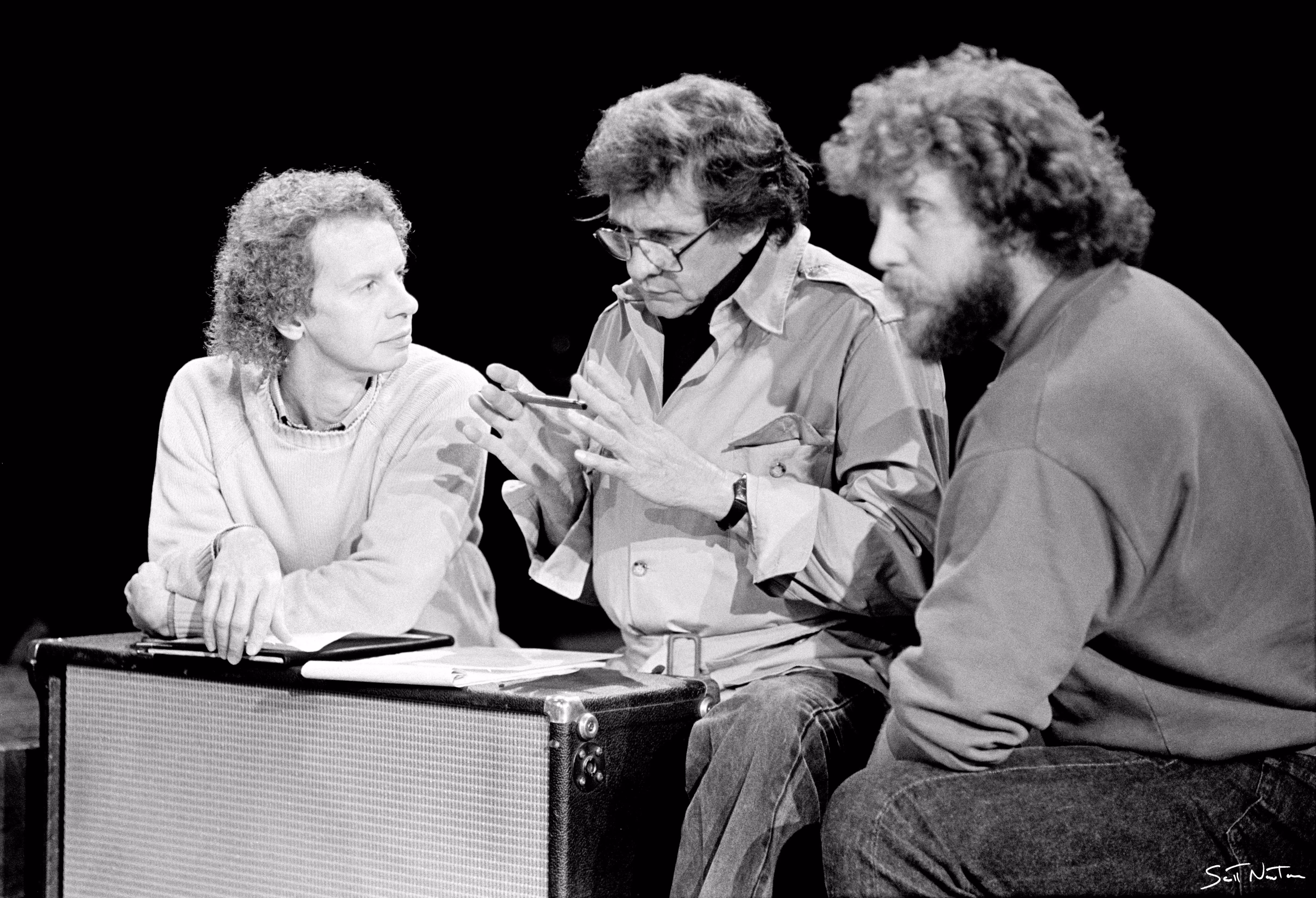 An archival photograph of three men engaged in a conversation.