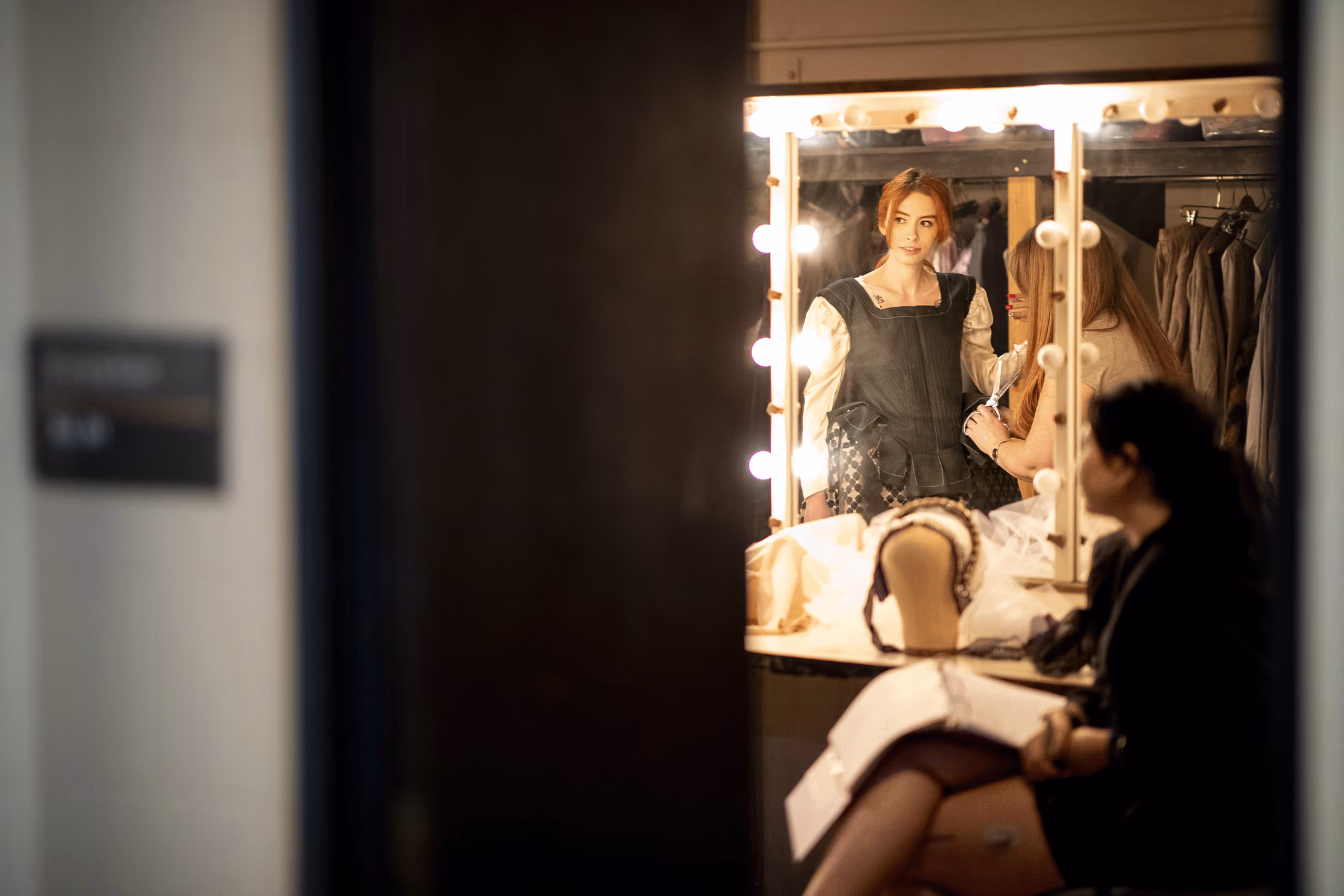 A student actor looks at the fit of her costume in the make-up mirror.