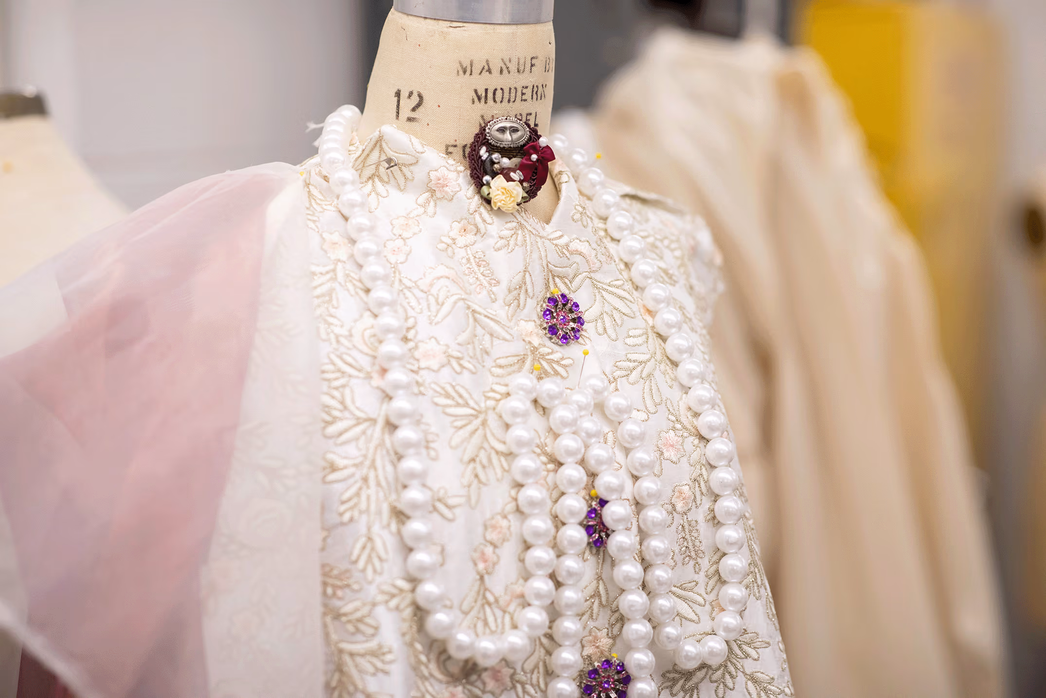 A close up of a intricate costume with pearl beading, sheer and embroidered fabric.