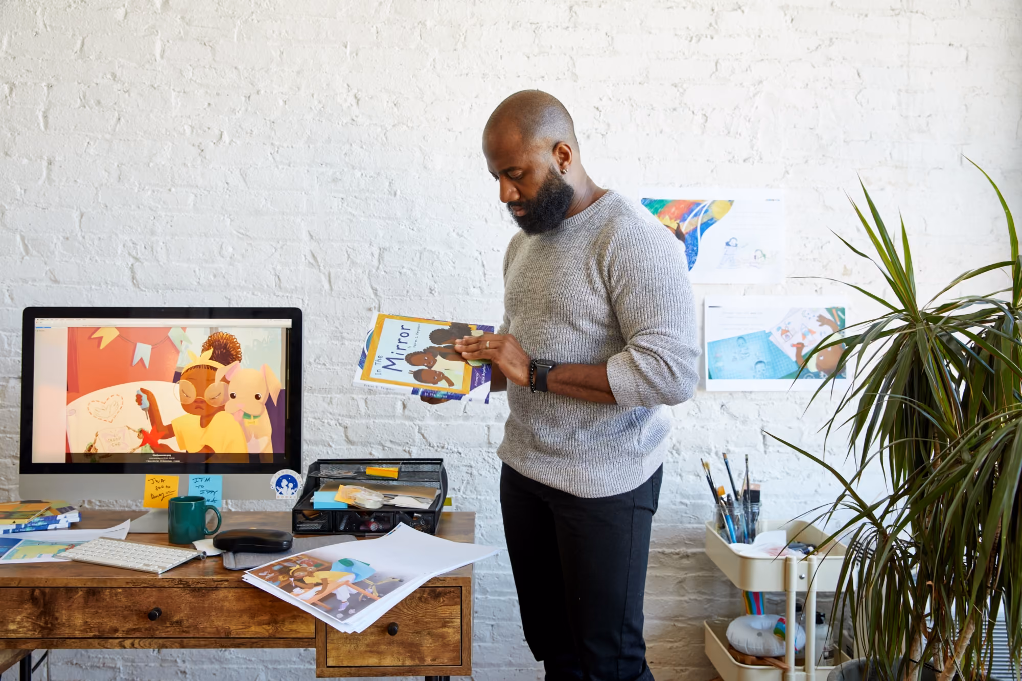 A montage of moving video shots of an African American child holding a children's book called "Daddy's Arms" that features an illustrated African American child on the cover.