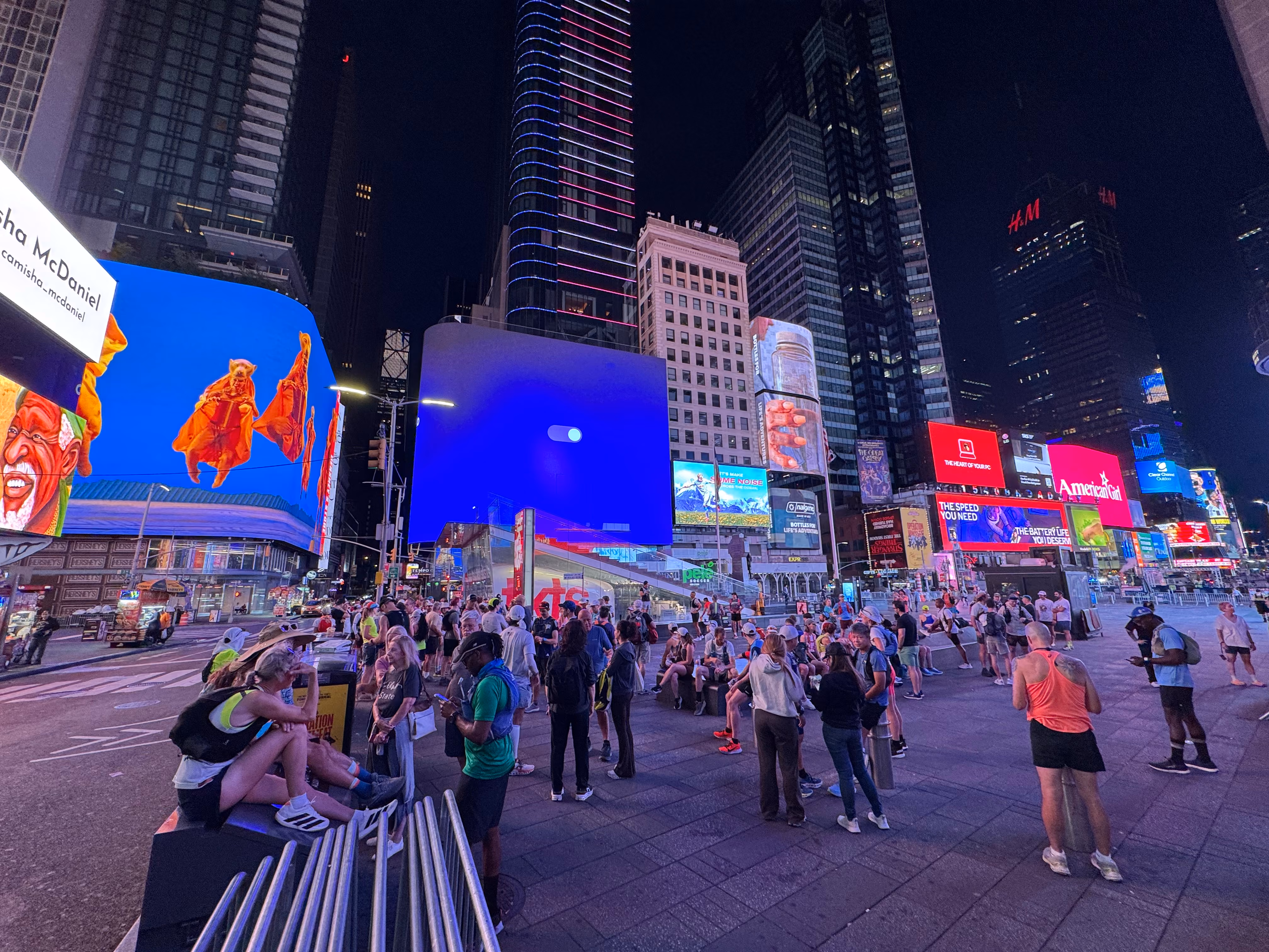Times Square, pre-dawn, is aglow with the light of massive screens as runners gather for the ultramarathon.