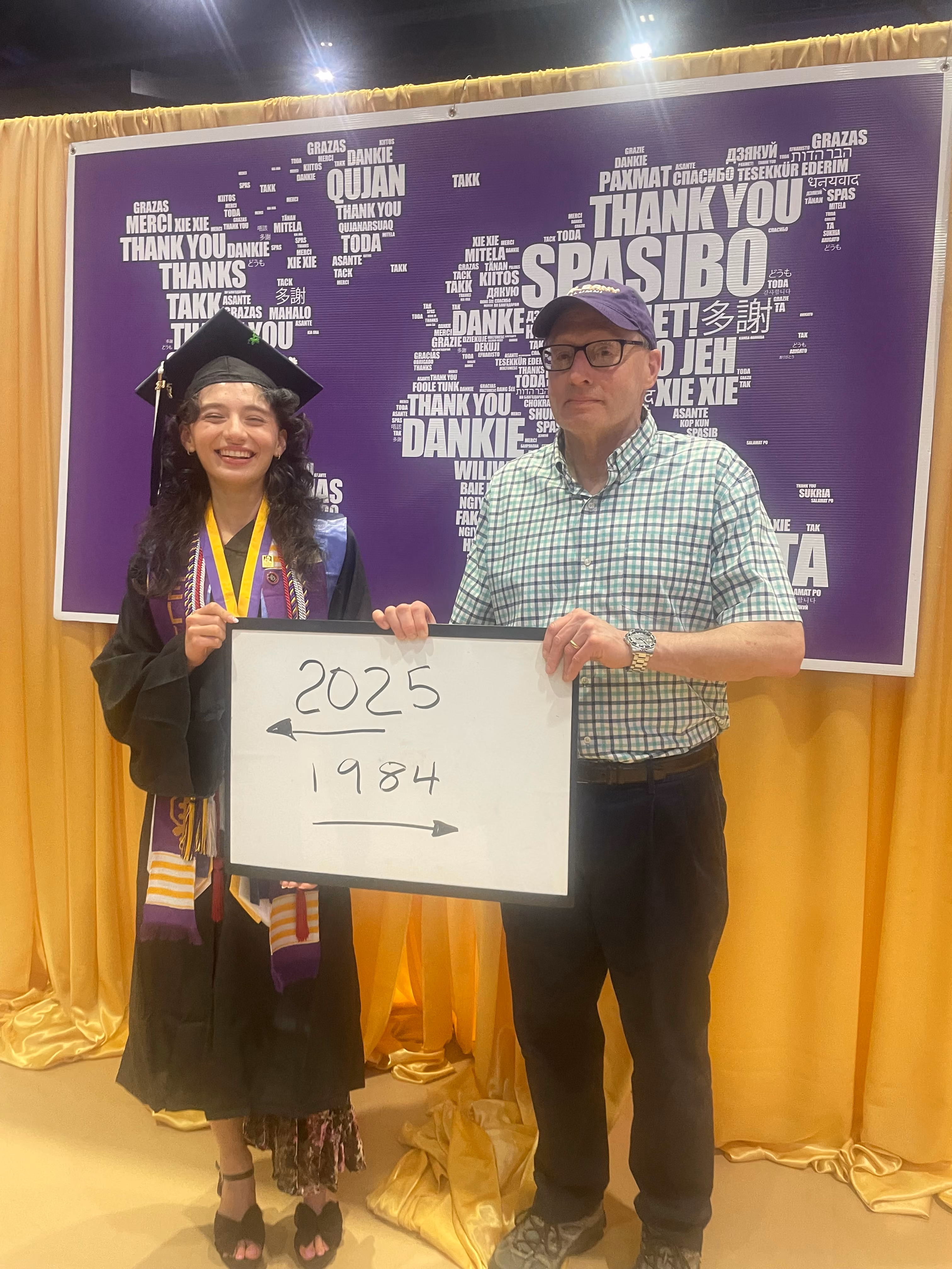 UAlbany grad Cecilia Hayes wears a graduation cap and gown and stands with her father, James Hayes ’84.