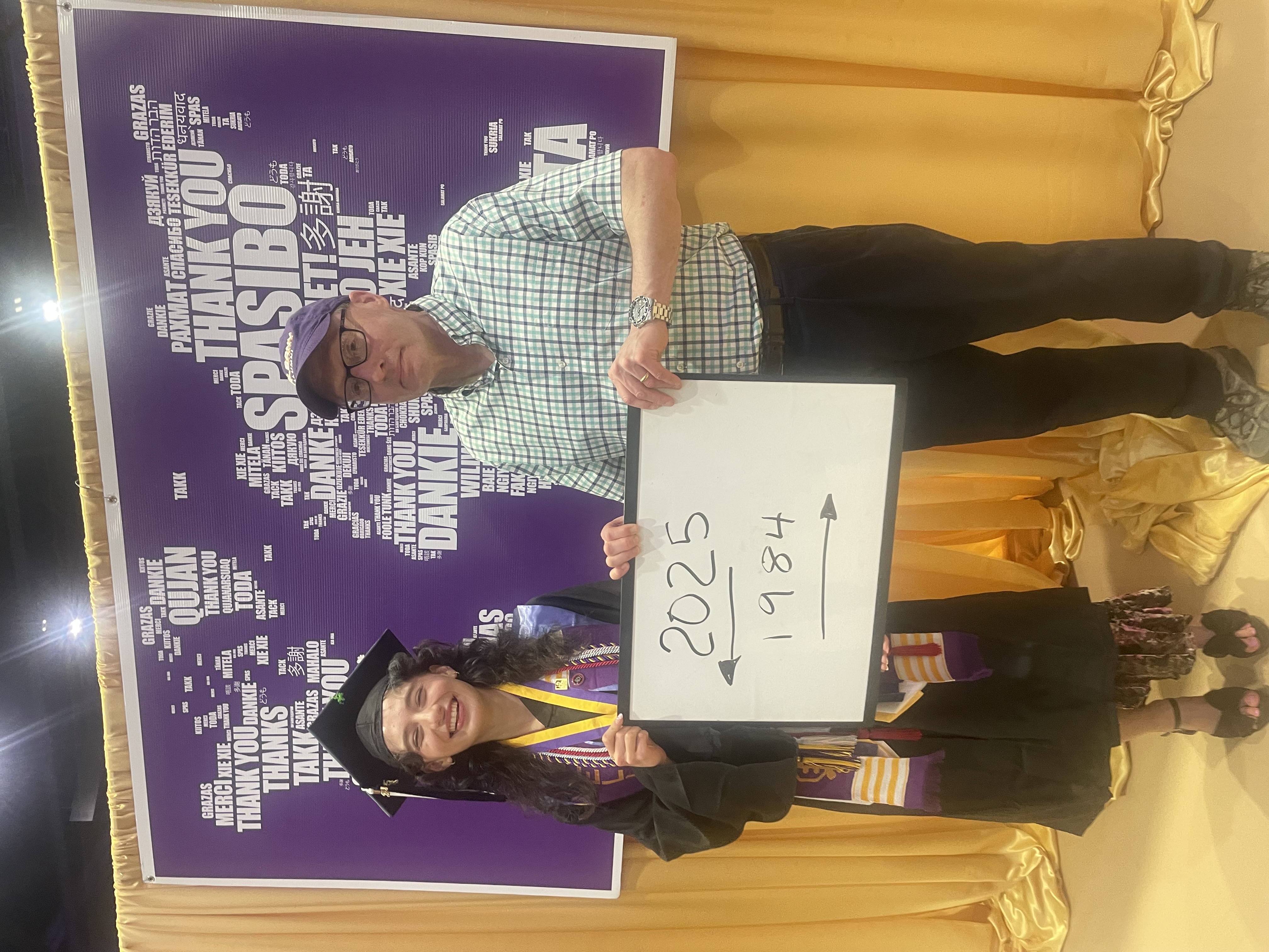 UAlbany grad Cecilia Hayes wears a graduation cap and gown and stands with her father, James Hayes ’84.