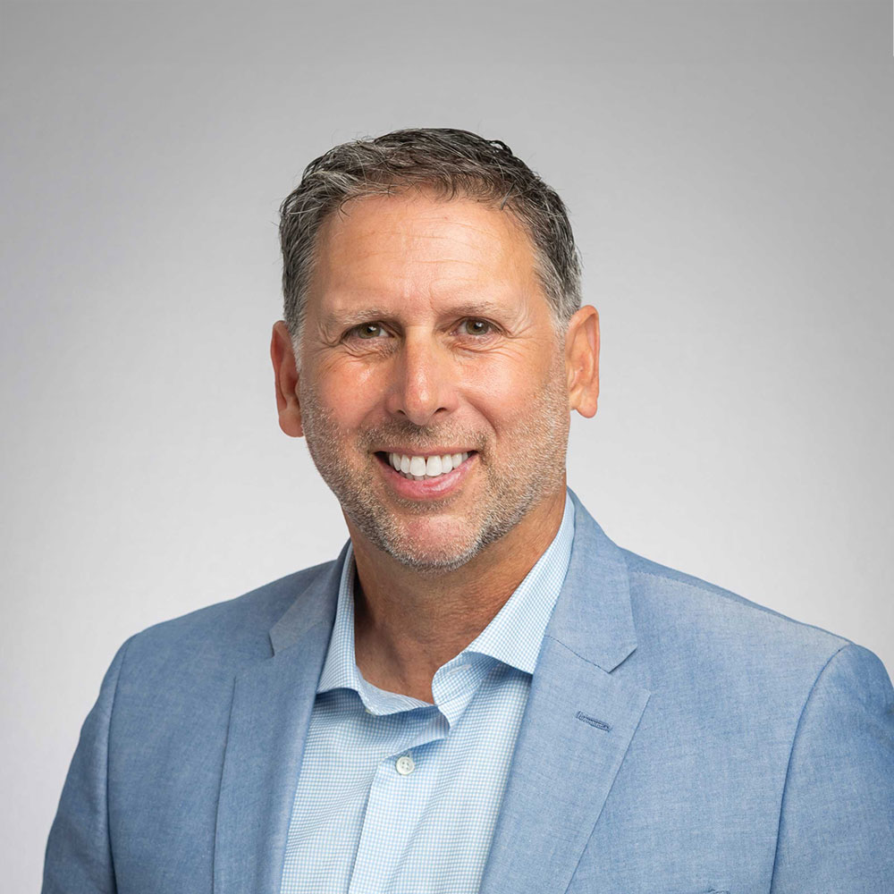 a portrait of a smiling white male, Michael Weiss, dressed in a sport coat and dress shirt, no tie.
