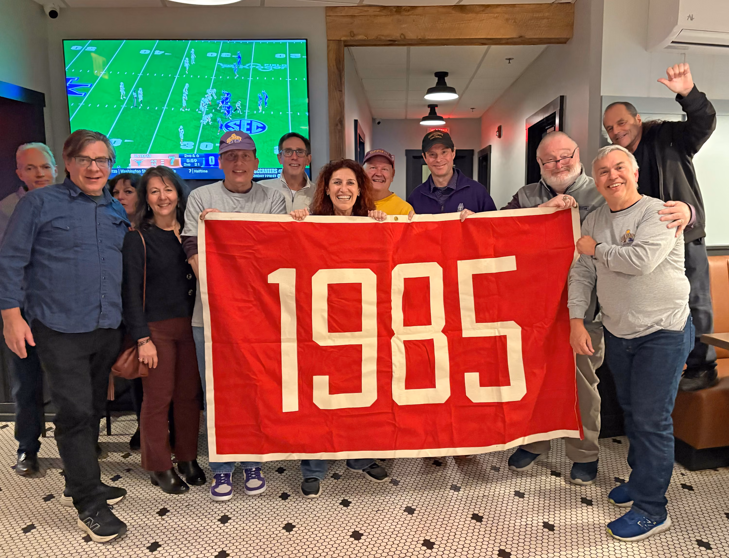 A group of classmates hold a 1985 banner.