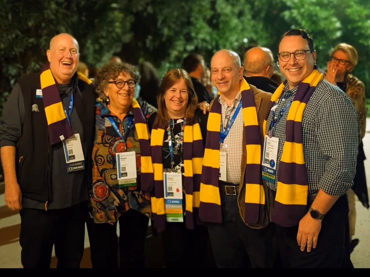 A group of friends wearing purple and gold scarves.