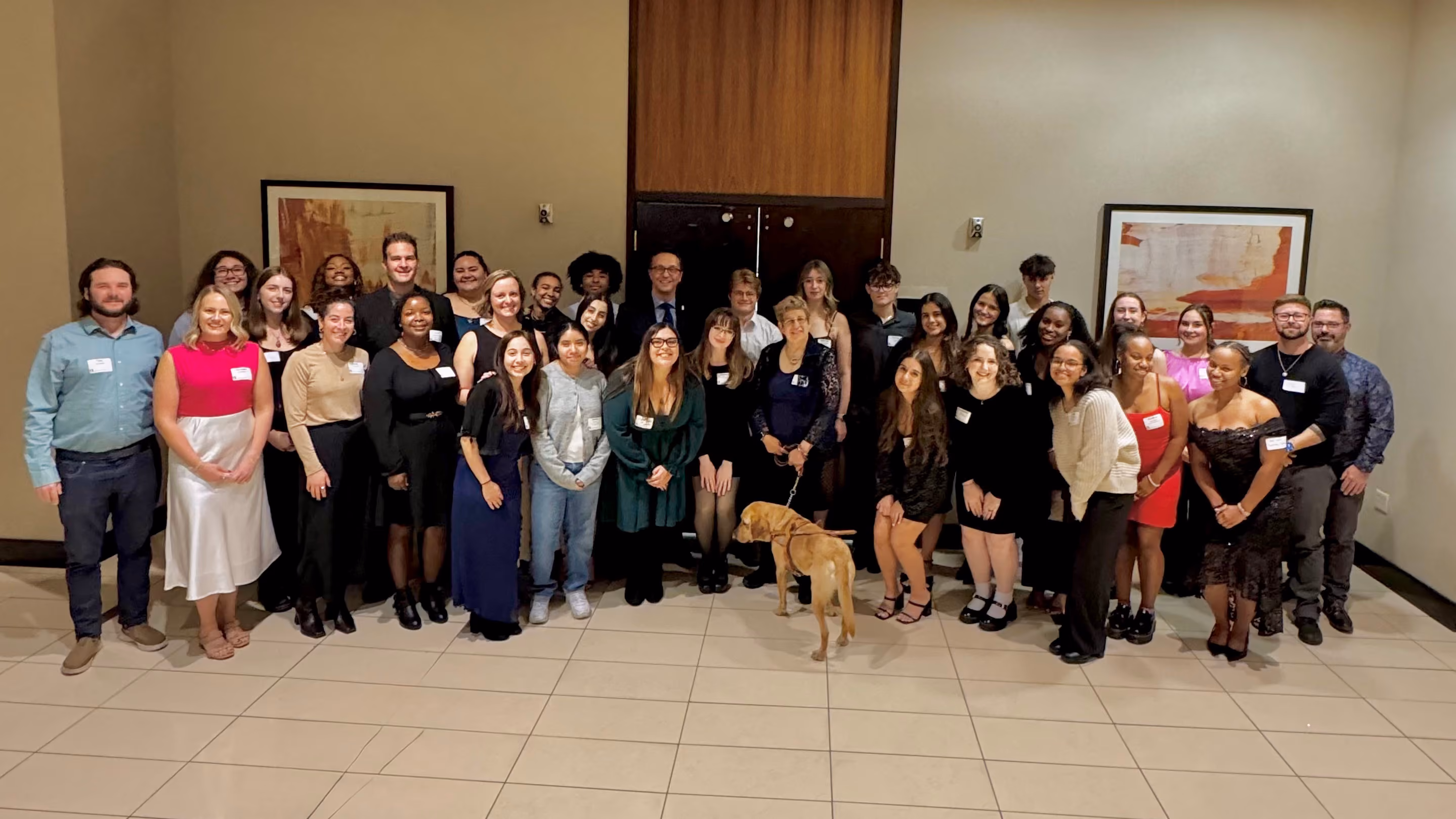 A large group of people gathered for a photo inside a ballroom.