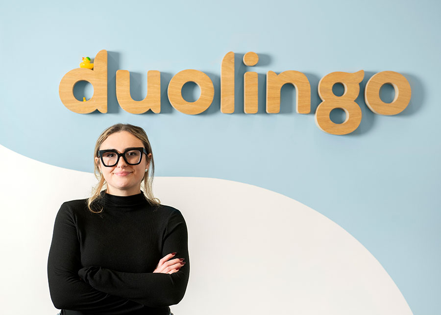 Adelen Touhey in front of a duolingo wall sign.