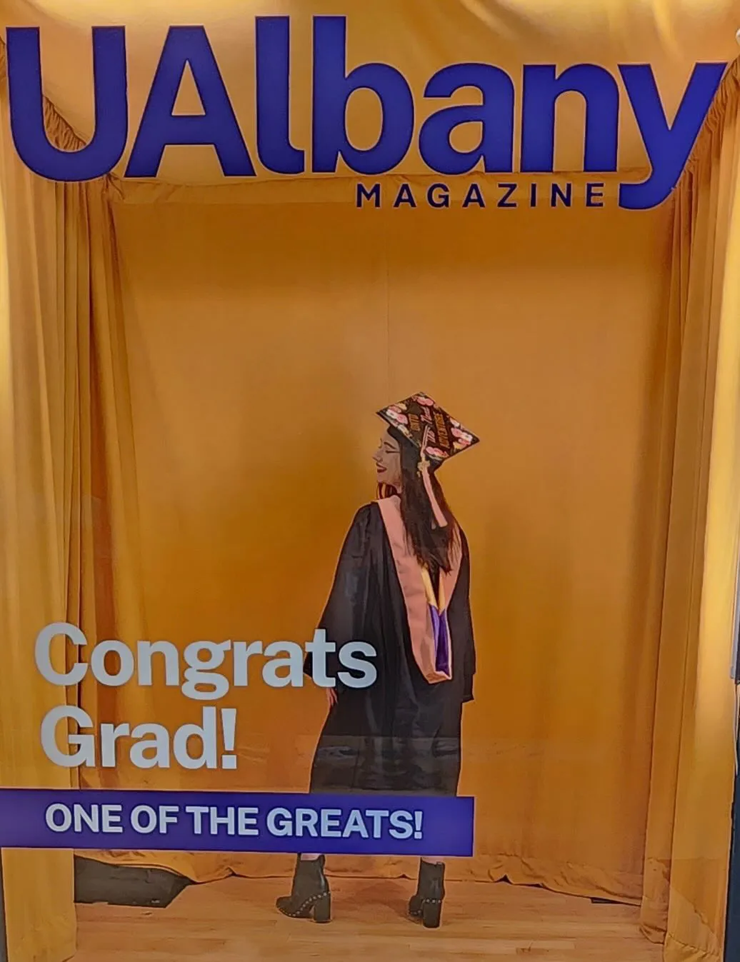 A grad shows off her regalia while posing for a photo in the booth.