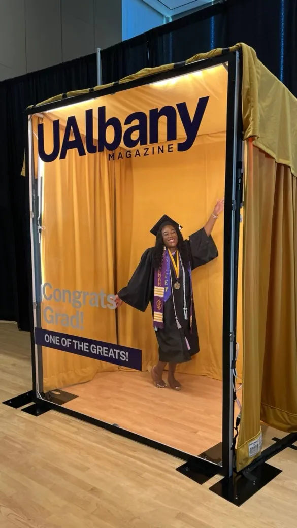 A grad waves while posing in the photo booth.